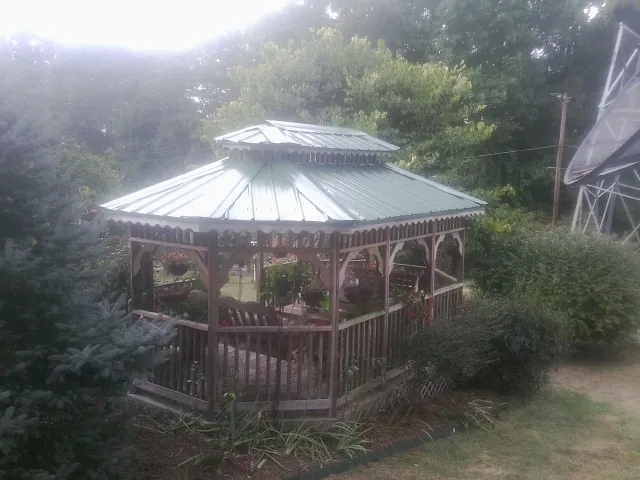 Green metal roof on a backyard gazebo surrounded by garden beds in Bremen