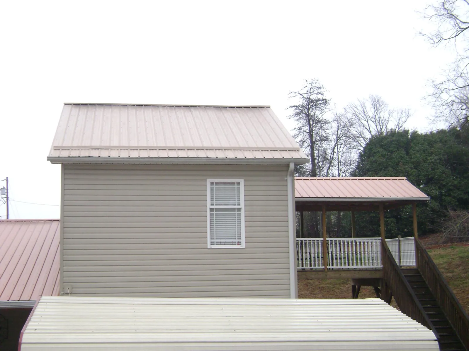 Tan metal roofs on a two story addition and attached porch, from a Roof Replacement job in Bremen